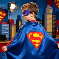Child wearing a blue superhero cape and purple eye mask