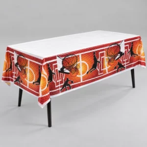 White basketball tablecloth with orange court, hoop and player silhouette borders draped over a rectangular table on a grey background