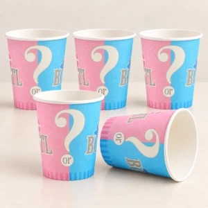Five pink and blue gender reveal paper cups on a pale tabletop, with one cup on its side