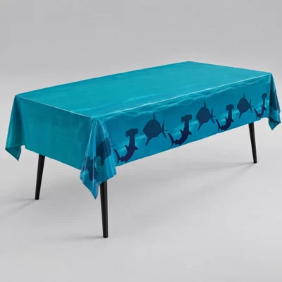 Teal tablecover with dark blue shark silhouette borders draped over a rectangular table on a grey background